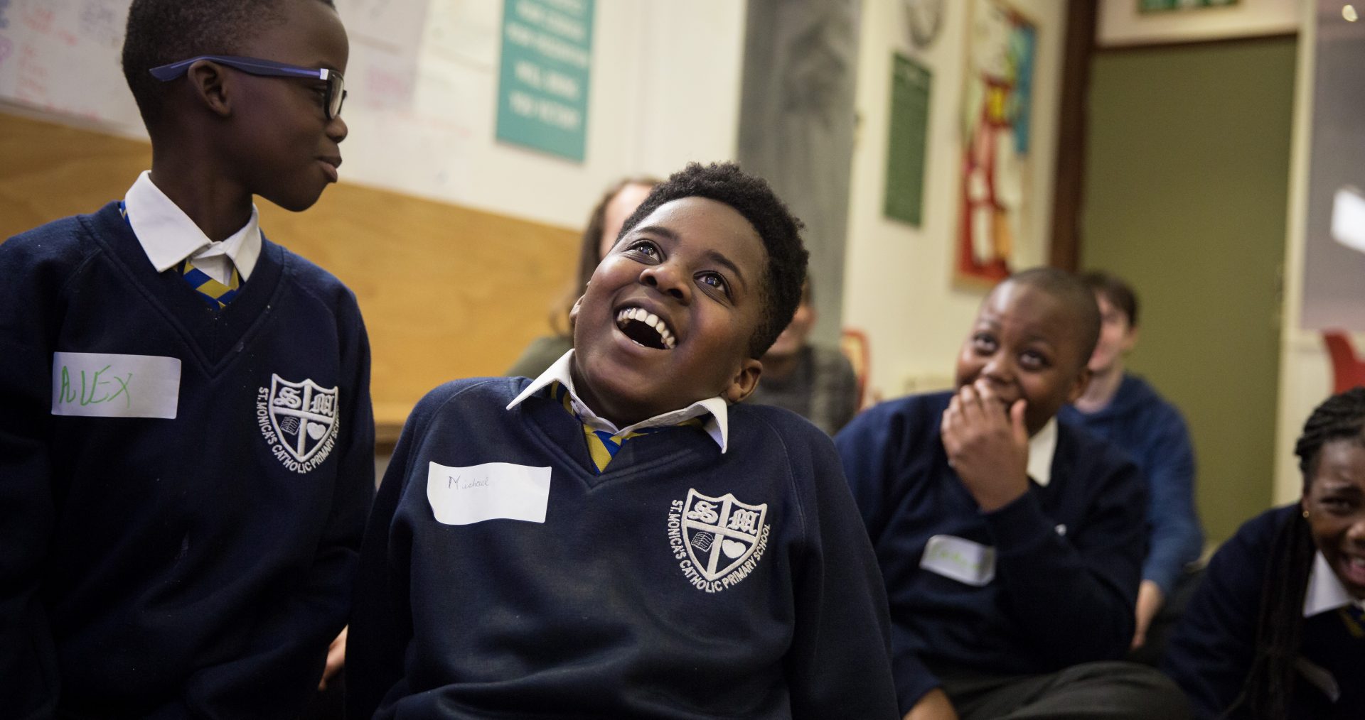 Three young boys laugh while sitting in the ministry of Stories