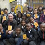 Nick Hornby with a crowd of young writers posing in front of the Children's Republic of Shoreditch temporary shopfront.