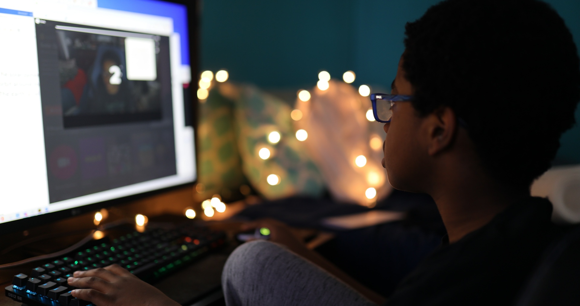 A boy sits at a computer screen
