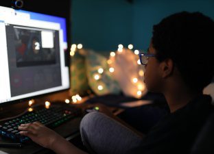 A boy sits at a computer screen