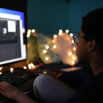 A boy sits at a computer screen