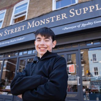Cian grins broadly in front of the Ministry of Stories building