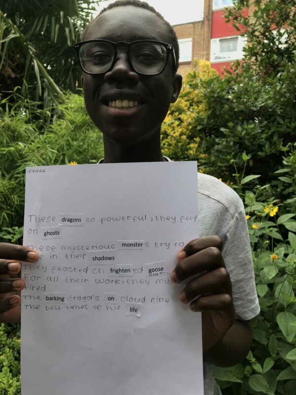 A young writer proudly holds up a sheet showing his poetry written that morning in the garden