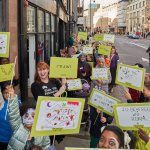 A long line of placards and smiling faces can be seen taking up the entire pavement on Hoxton Street