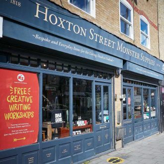 A long, retro shop front painted in a dark blue with gold lettering reading Hoxton Street Monster Supplies