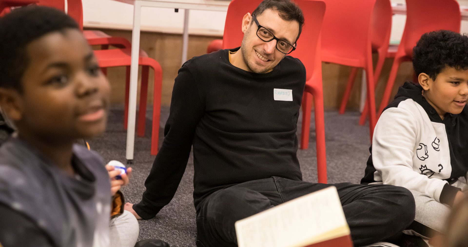 Volunteer sat on carpet listening to young writer present