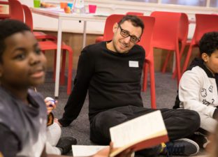 Volunteer sat on carpet listening to young writer present