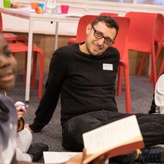 Volunteer sat on carpet listening to young writer present