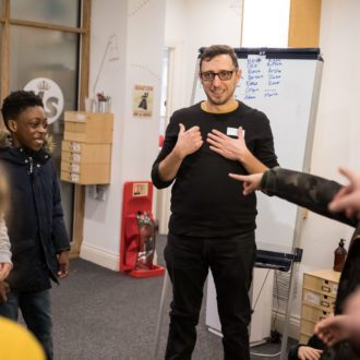 Volunteer writing mentor being pointed at by young writers as they play a game