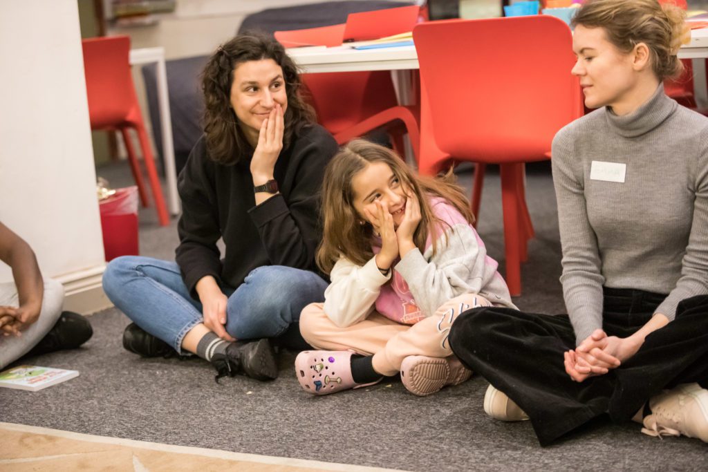 volunteer writing mentor and young person looking to the right with hands over face.