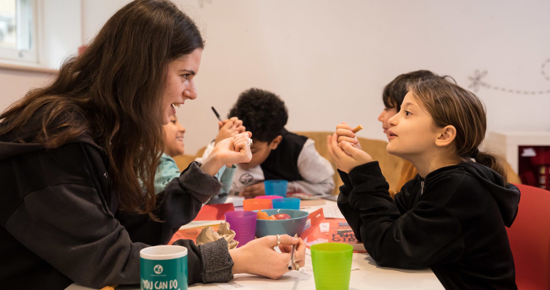 Volunteer writing mentor and young writer look at each other across the table