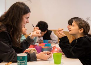 Volunteer writing mentor and young writer look at each other across the table