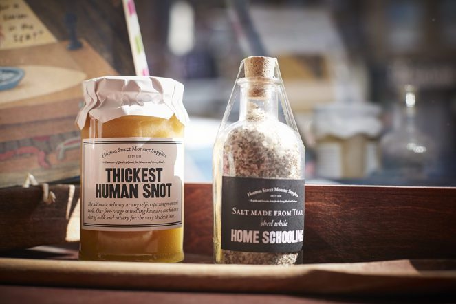 Two products in a corked bottle and screw top jar sit in the sun on a wooden shelf 