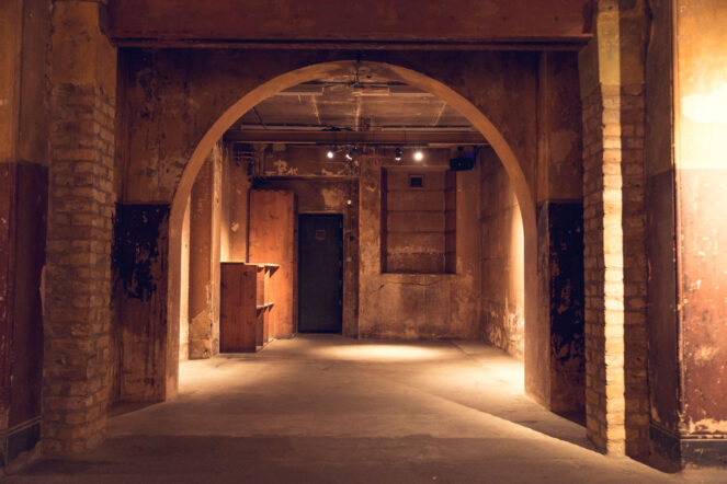 An arch in a rundown basement type environment glows invitingly. 