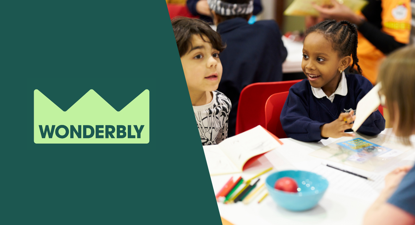 Wonderbly's logo sits alongside a picture of two young children chatting and writing together on a white table.