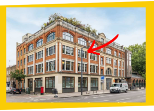 A grand, red brick, four story building sits next o the road. It has large, victorian windows and arches. There is a red arrow pointing to the second floor, showing where the new space for Ministry of Stories is.