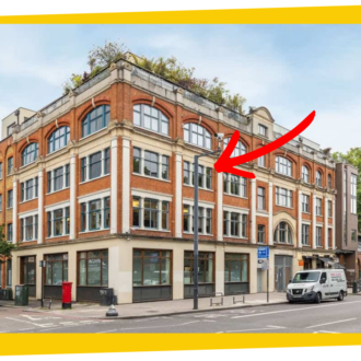 A grand, red brick, four story building sits next o the road. It has large, victorian windows and arches. There is a red arrow pointing to the second floor, showing where the new space for Ministry of Stories is.