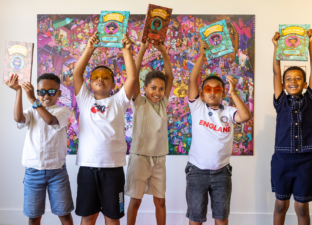 Five young writers hold their published story collections above their head on the red carpet at our celebration event.